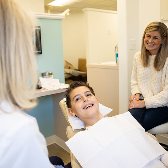 Young patient and his parent smiling with dentist