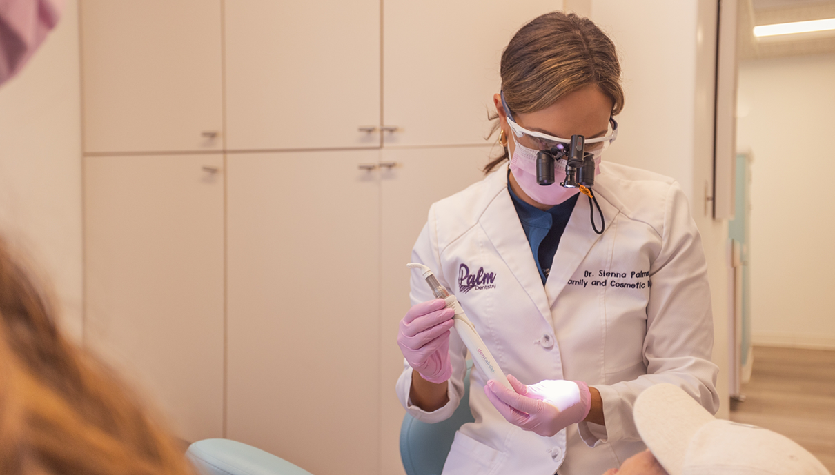 patient admiring her new smile in a mirror after getting dental crowns in Mission Viejo, CA
