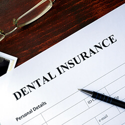 Dental insurance paperwork with pen and X-ray on table