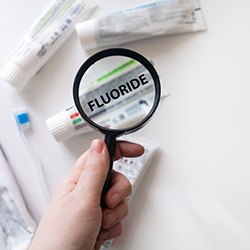 Magnifying glass over tubes of toothpaste with Fluoride written on it