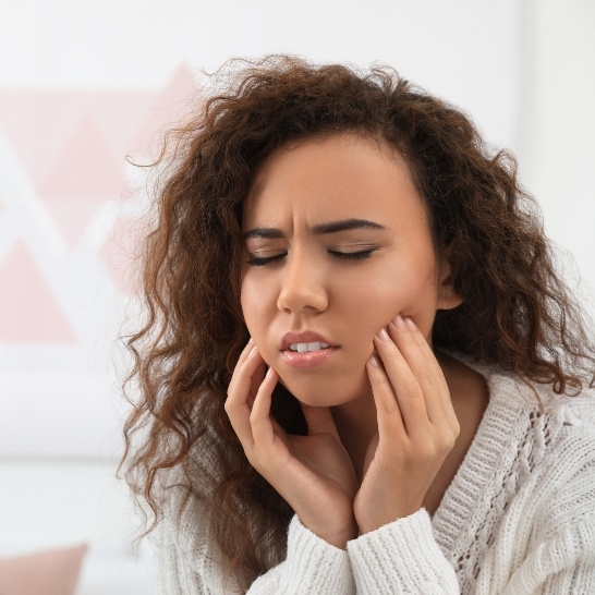 Woman in need of emergency dentistry holding jaw