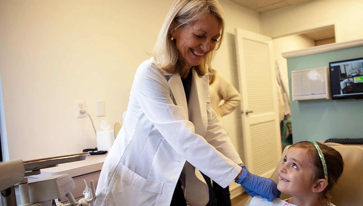 Dentist smiling at young girl during children's dentistry visit