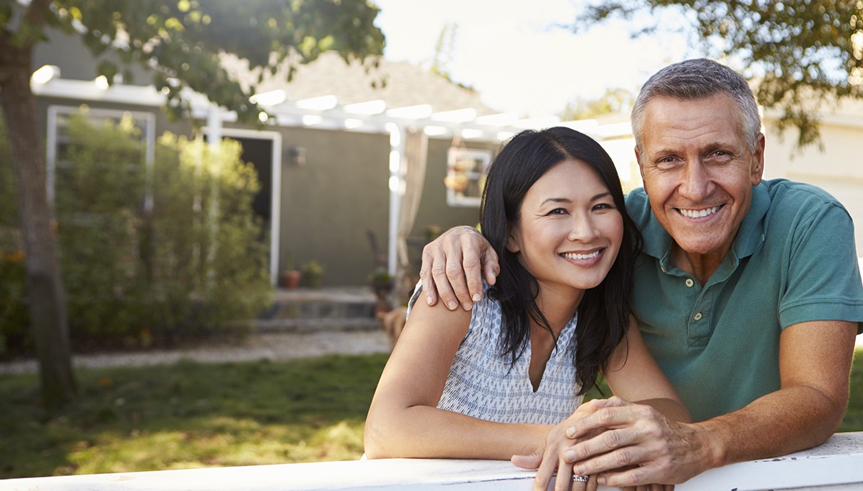 Man and woman smiling after replacing missing teeth