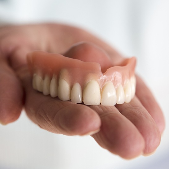 Hand holding a full denture