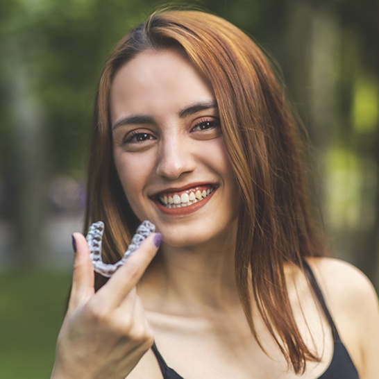 Woman holding an Invisalign clear braces tray