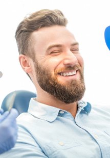 patient smiling while holding dental mirror 