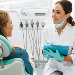 Dentist smiling while taking notes on clipboard