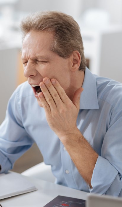 Man in need of emergency dentistry holding jaw