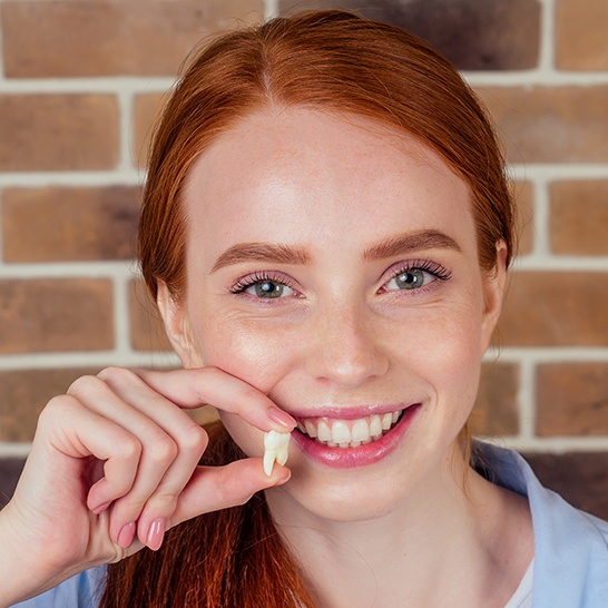 Woman holding up an extracted tooth