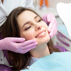 : a patient smiling and checking her veneers with a mirror