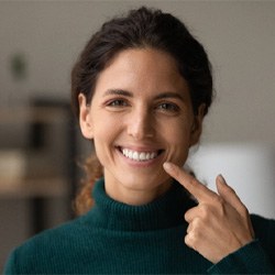 a woman smiling and pointing at her veneersor