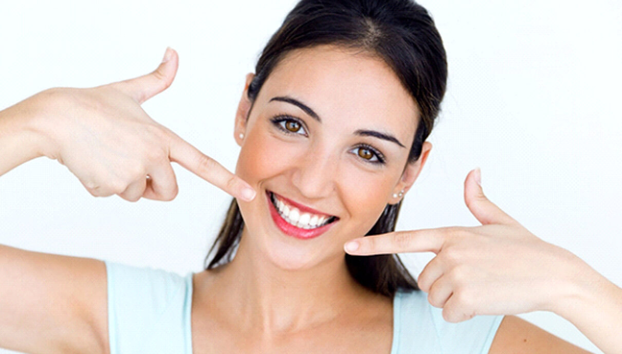 woman pointing to her smile with veneers in Mission Viejo