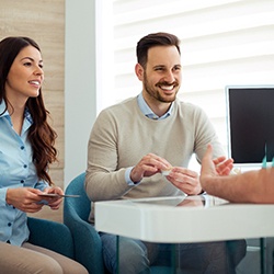 a couple discussing cost of teeth whitening with the dentist