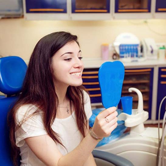 young woman admiring her smile after teeth whitening in Mission Viejo