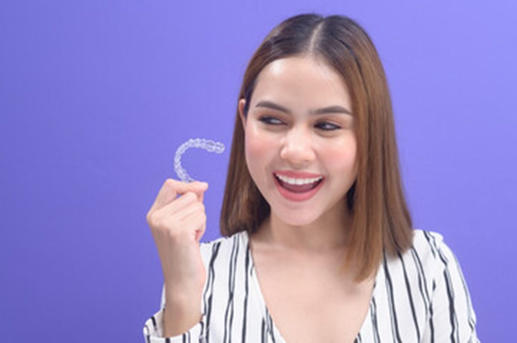 Woman removing her Invisalign aligner.