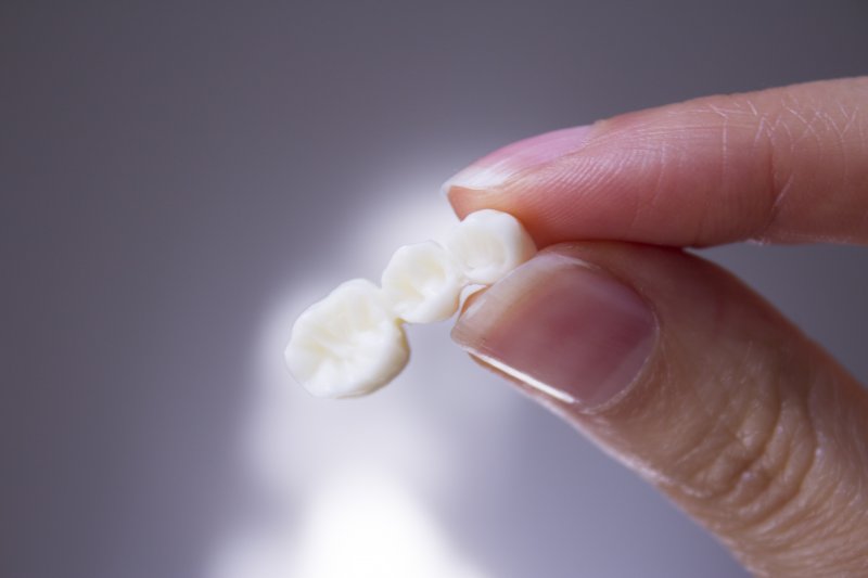 A hand holding a dental bridge that fell out