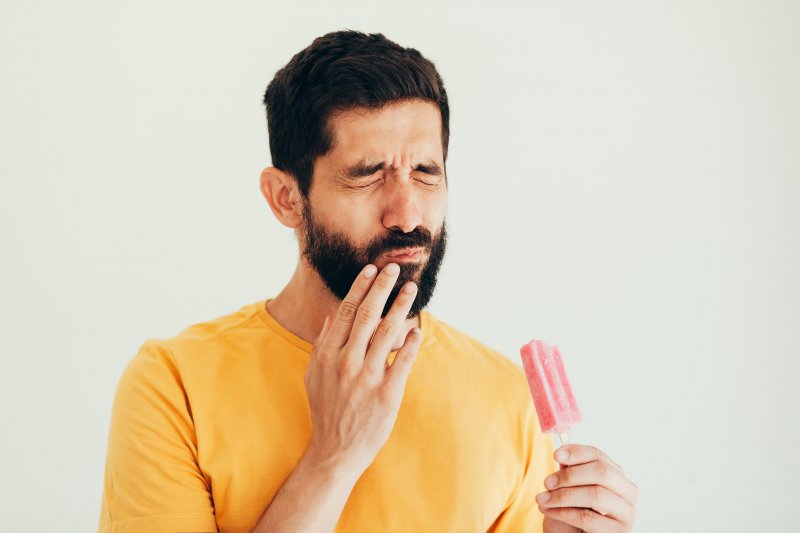 man eating a popsicle and wincing
