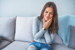 Woman holding side of face in pain.