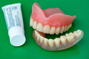 Dentures next to a tube of denture adhesive cream