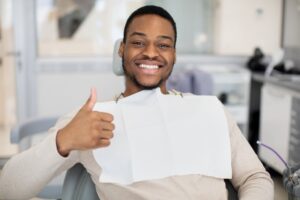 Man at the dentist smiling and holding a thumbs up